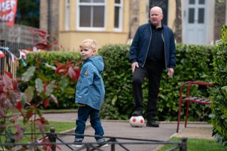 Phil Mitchell kicking a football with son Albie in Albert Square