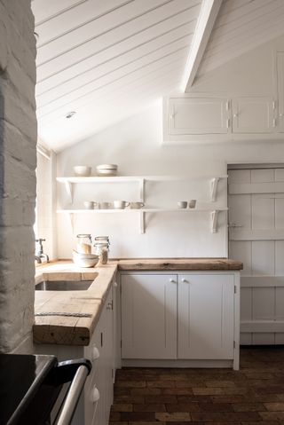 Wooden worktop in white kitchen with open shelves