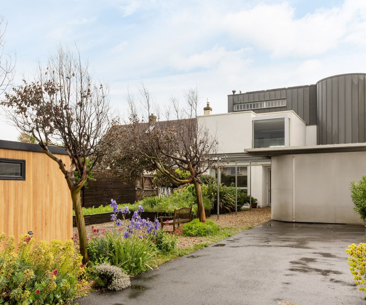 A gravelled garden with two trees on the path leading to a garden room