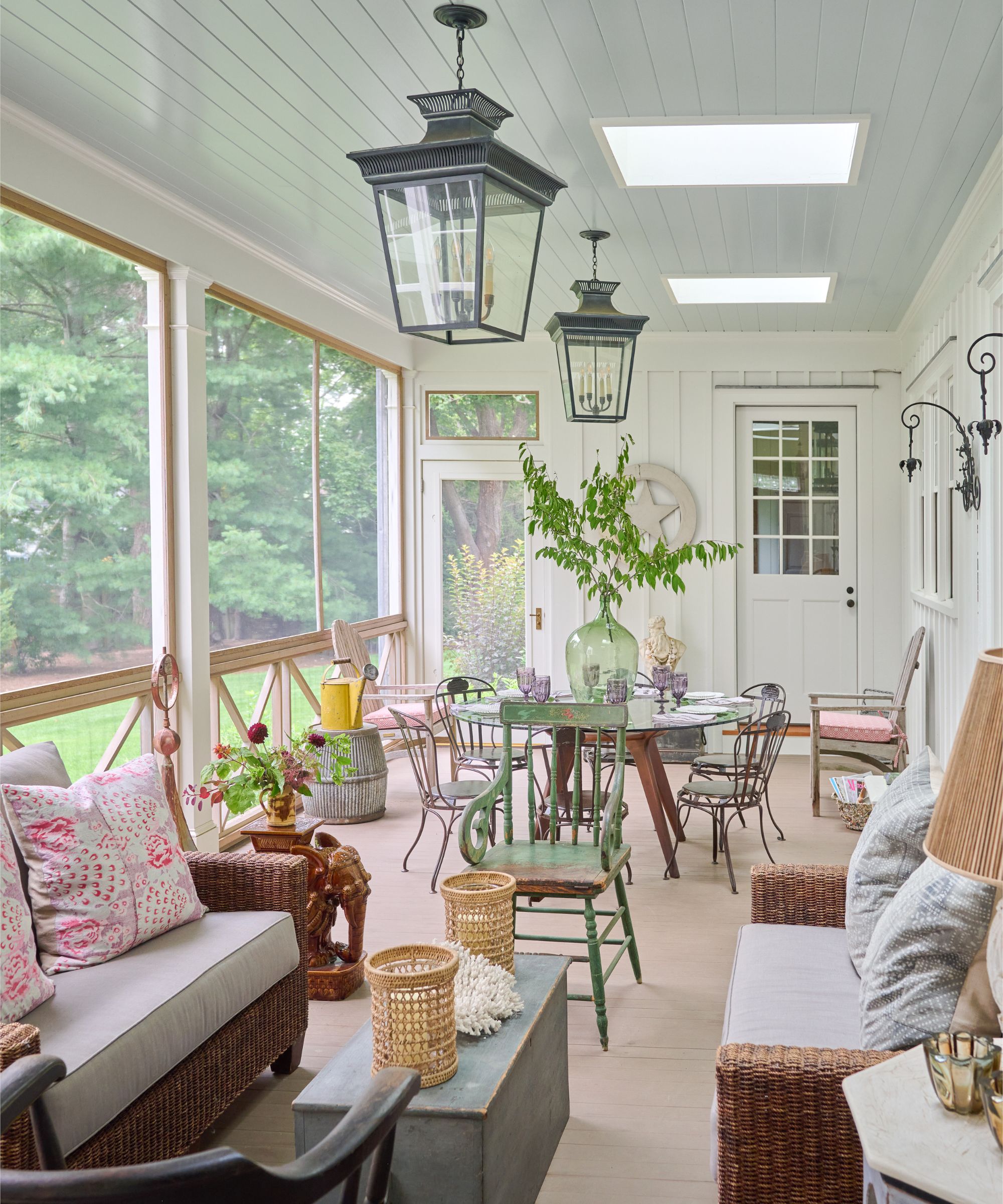 White wood panelled Sunroom with vintage furniture and a dining and seating area