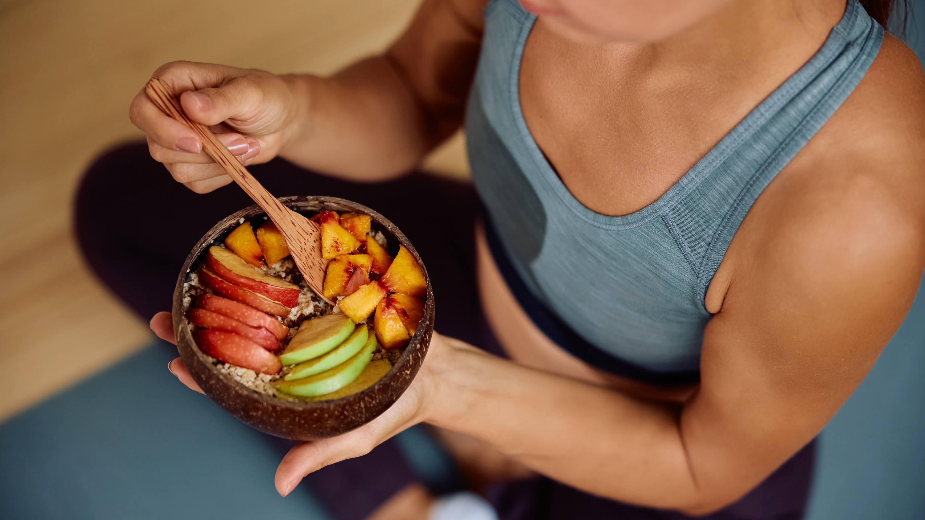 a woman eating a granola and fruit bowl