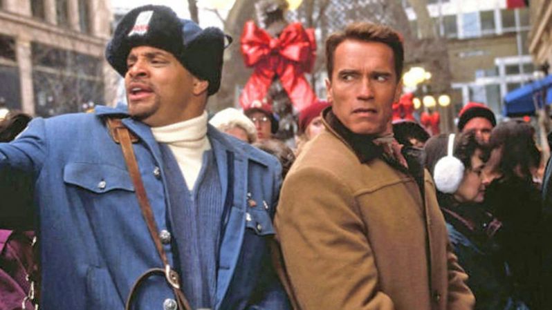 Sinbad (left) and Arnold Schwarzenegger stand in a crowd in a scene from &quot;Jingle All the Way&quot;