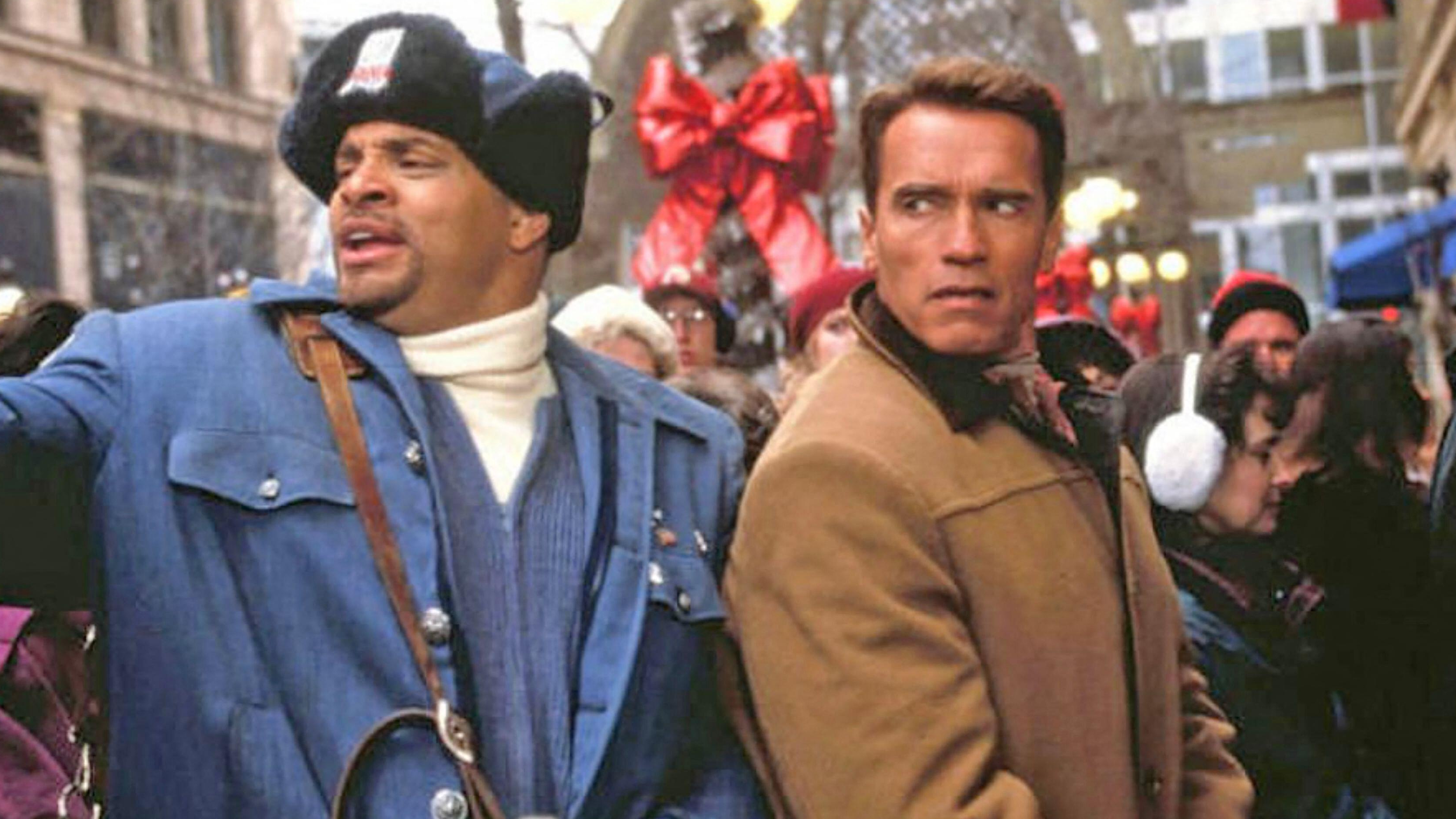 Sinbad (left) and Arnold Schwarzenegger stand in a crowd in a scene from &quot;Jingle All the Way&quot;