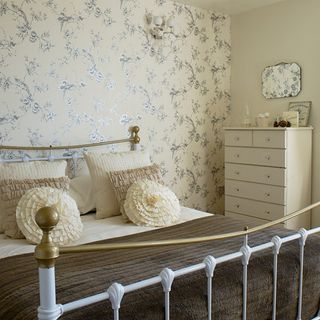 brass bed and cream and silver floral wallpaper