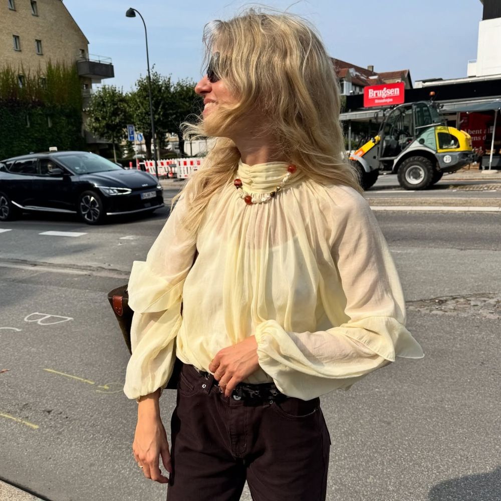 Influencer @josephinebredsted wears a butter yellow blouse with burgundy jeans and brown suede shoes.
