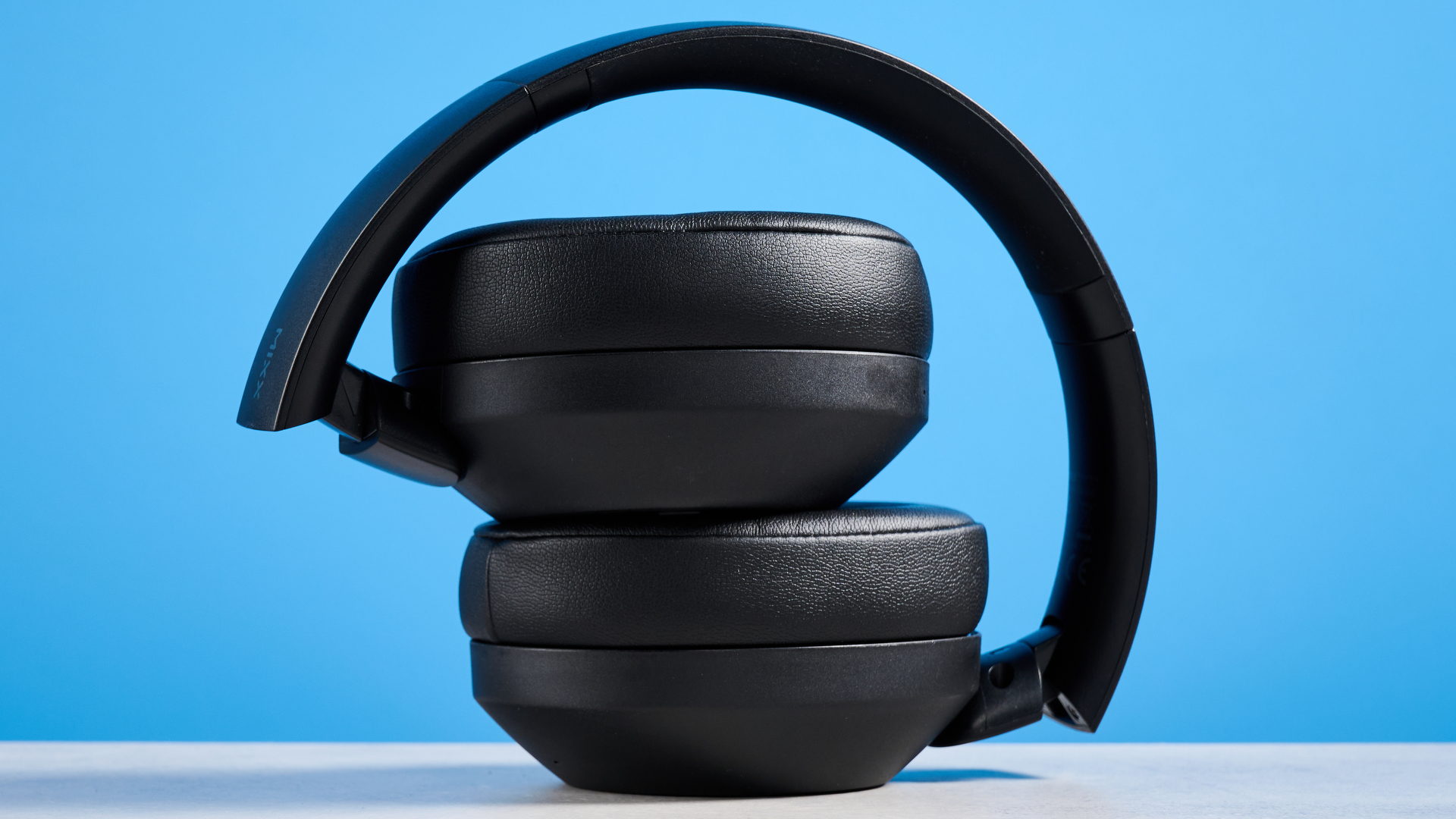 the mixx streamq c4 headphones in black with a blue background showing the soft cups and buttons controls