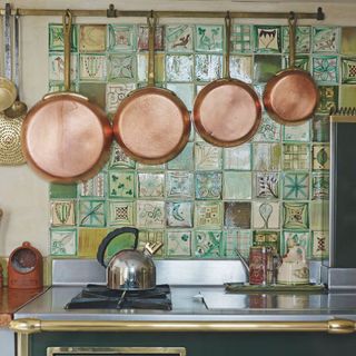 french style kitchen with copper saucepans and utensils hanging on tiled wall