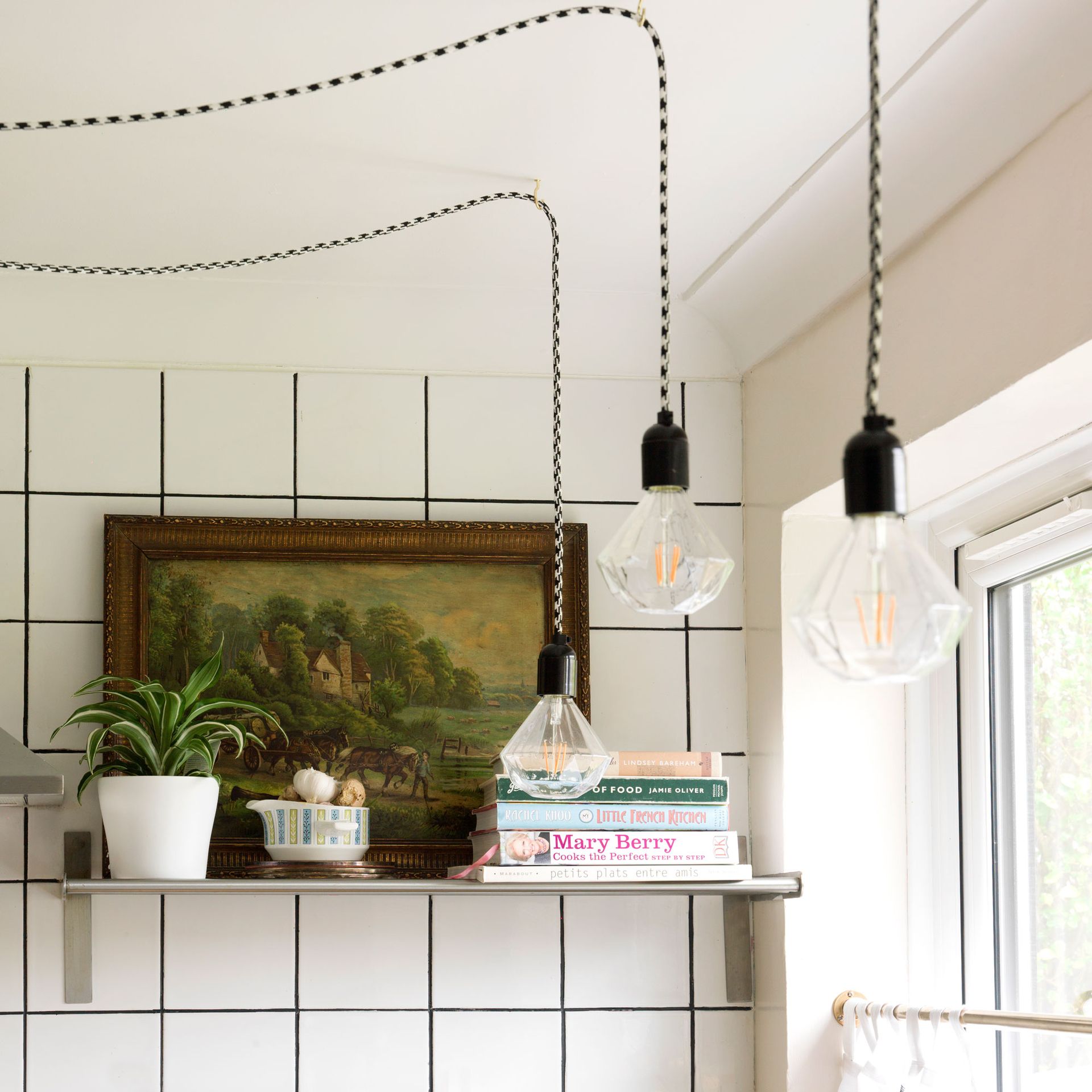 white tiled kitchen with open shelving and exposed bulbs