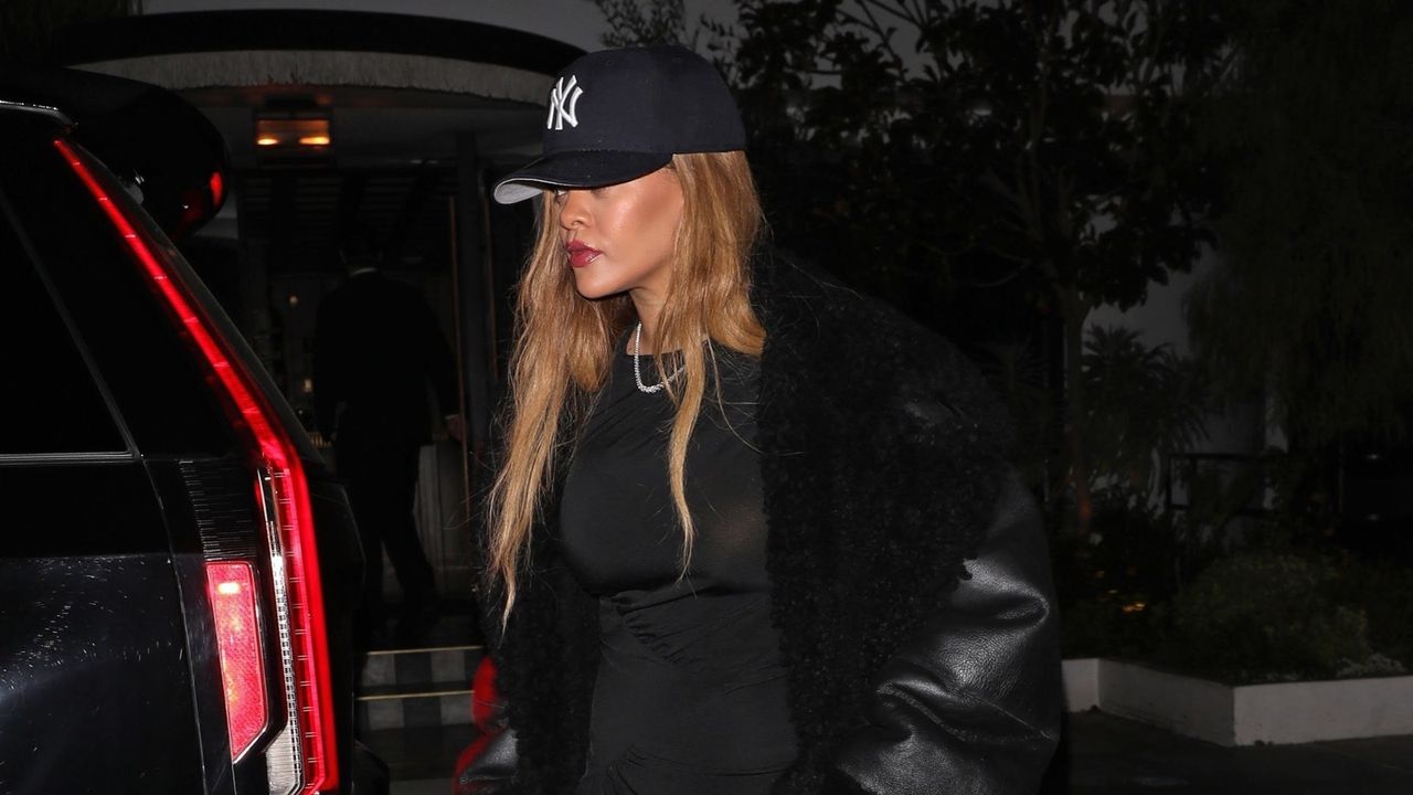 Rihanna wearing a little black dress with a NY baseball hat