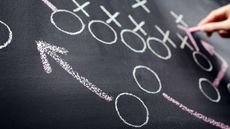 person drawing football plays on chalkboard