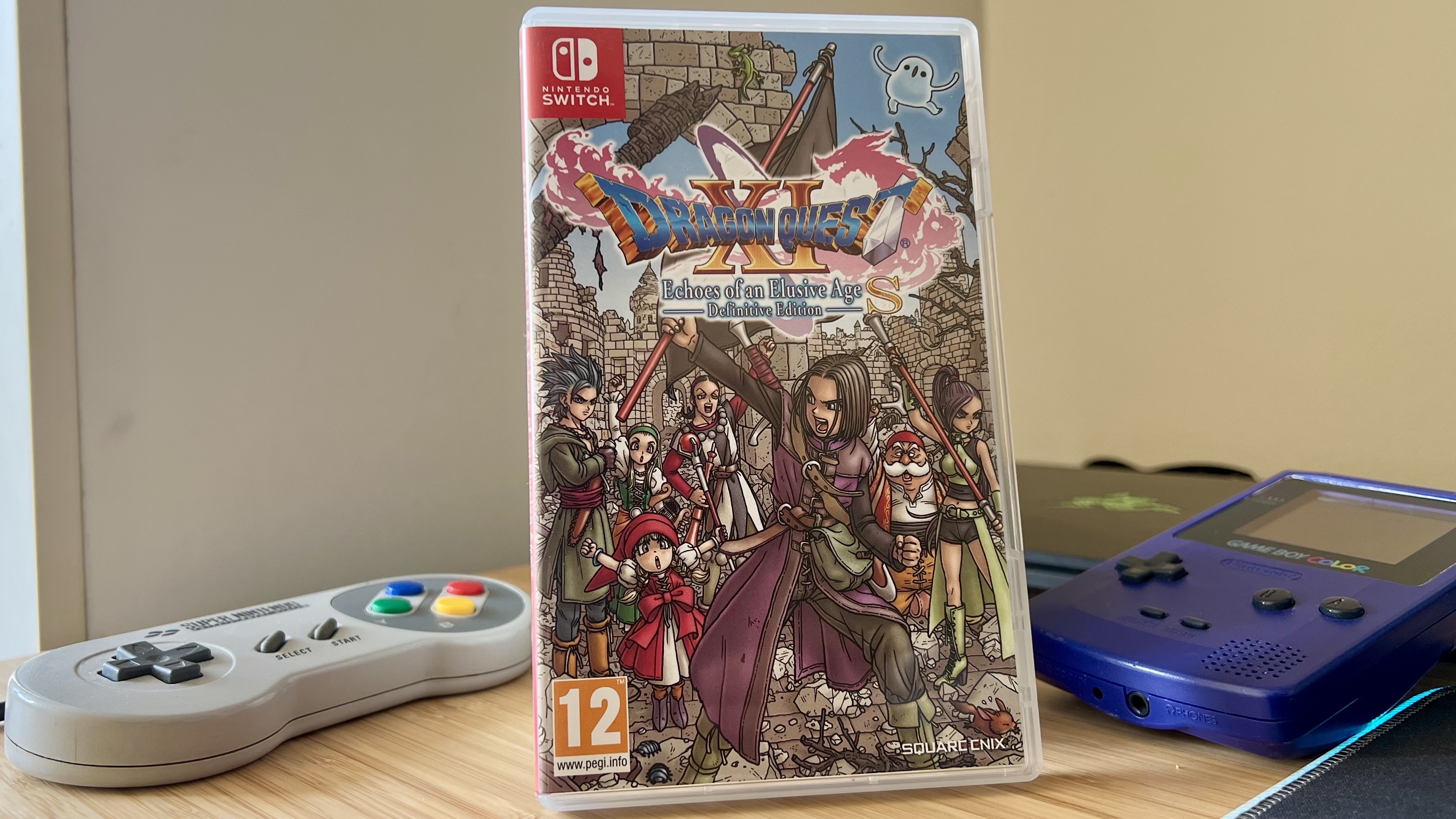 Dragon Quest XI S Nintendo Switch game on a wooden desk with SNES controller and Game Boy Color