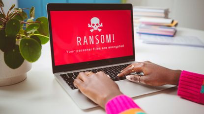A laptop with a red screen with a white skull on it with the message: "RANSOMWARE. All your files are encrypted."