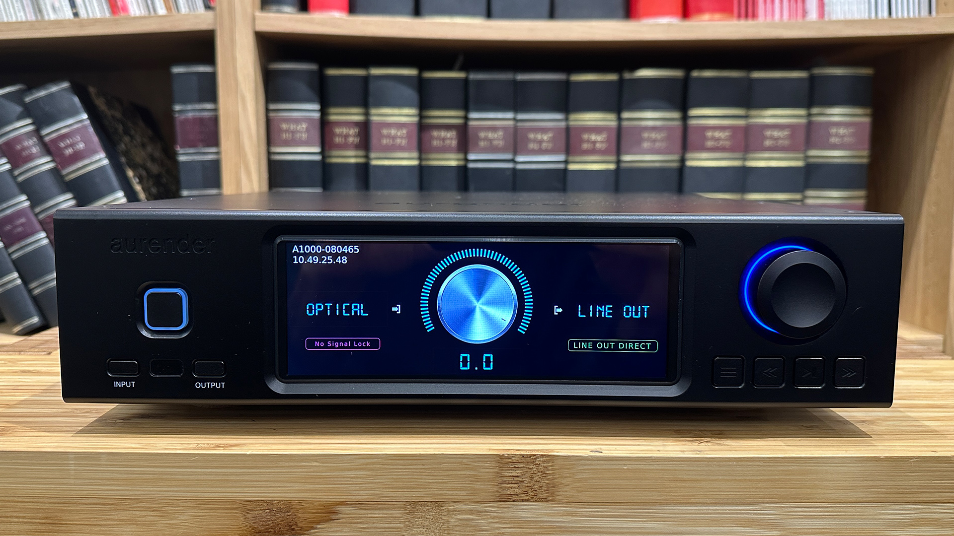 Aurender A1000 music streamer on wooden hi-fi rack in front of bookcase