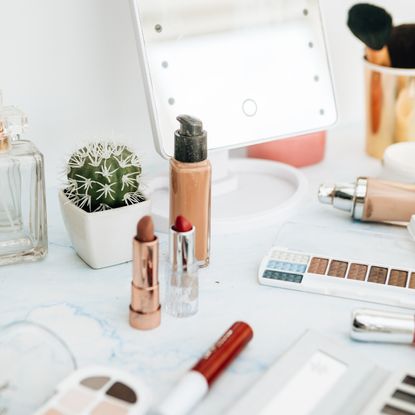 Image showing various make-up products, a beauty mirror, cactus and fragrance bottle on a dressing cable 