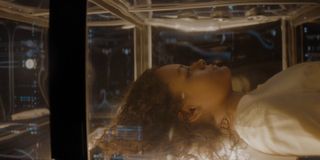 a girl lies in a computerized glass chamber