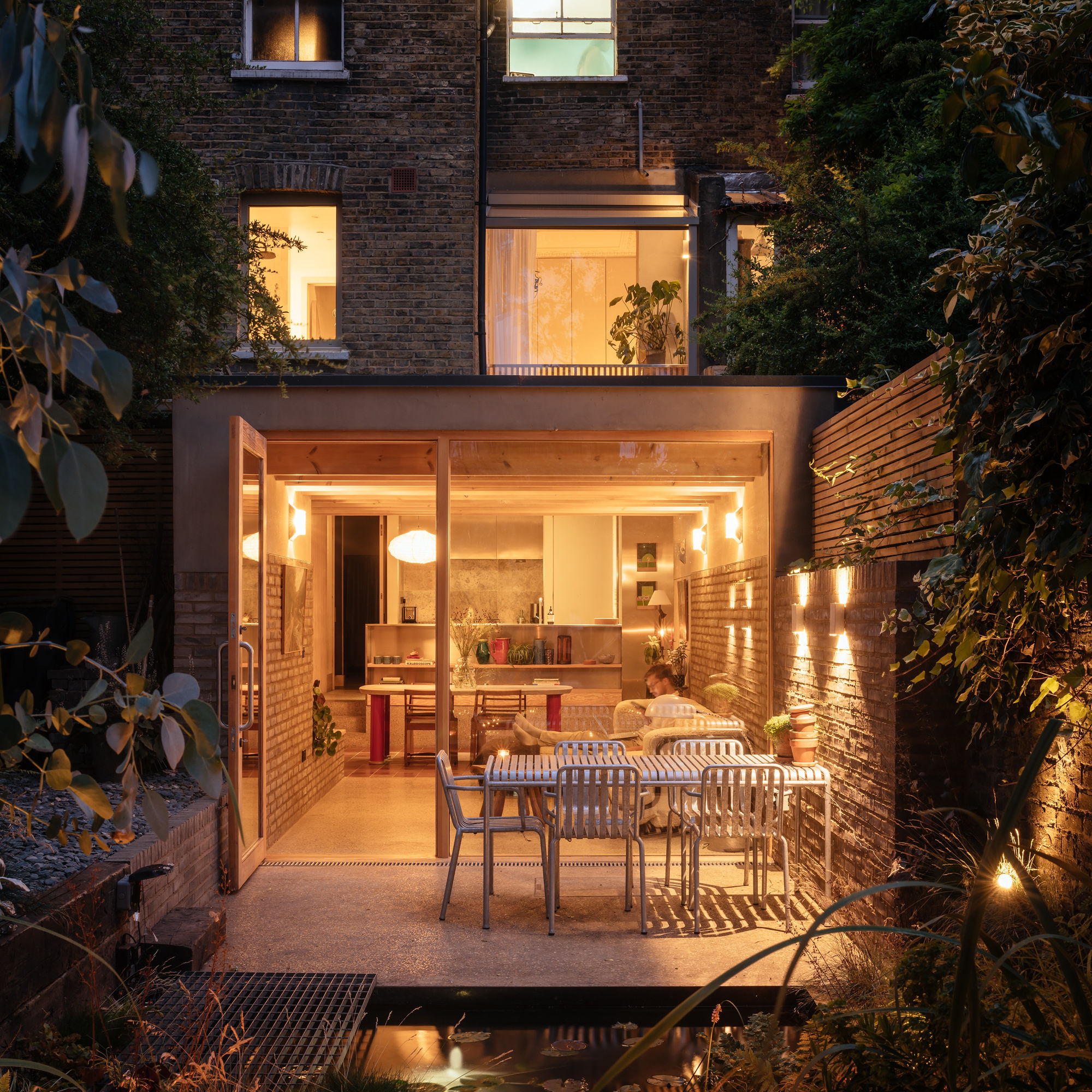 Kitchen extension lit up at night with patio and seating