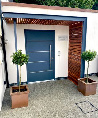 contemporary front porch with a modern blue front door and slatted timber sides
