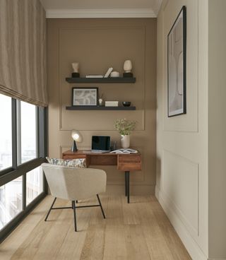 home office nook with panelled walls, glass wall on one side, wood desk, upholstered chair, cushion, wooden floor, 2 floating shelves, blind, artwork