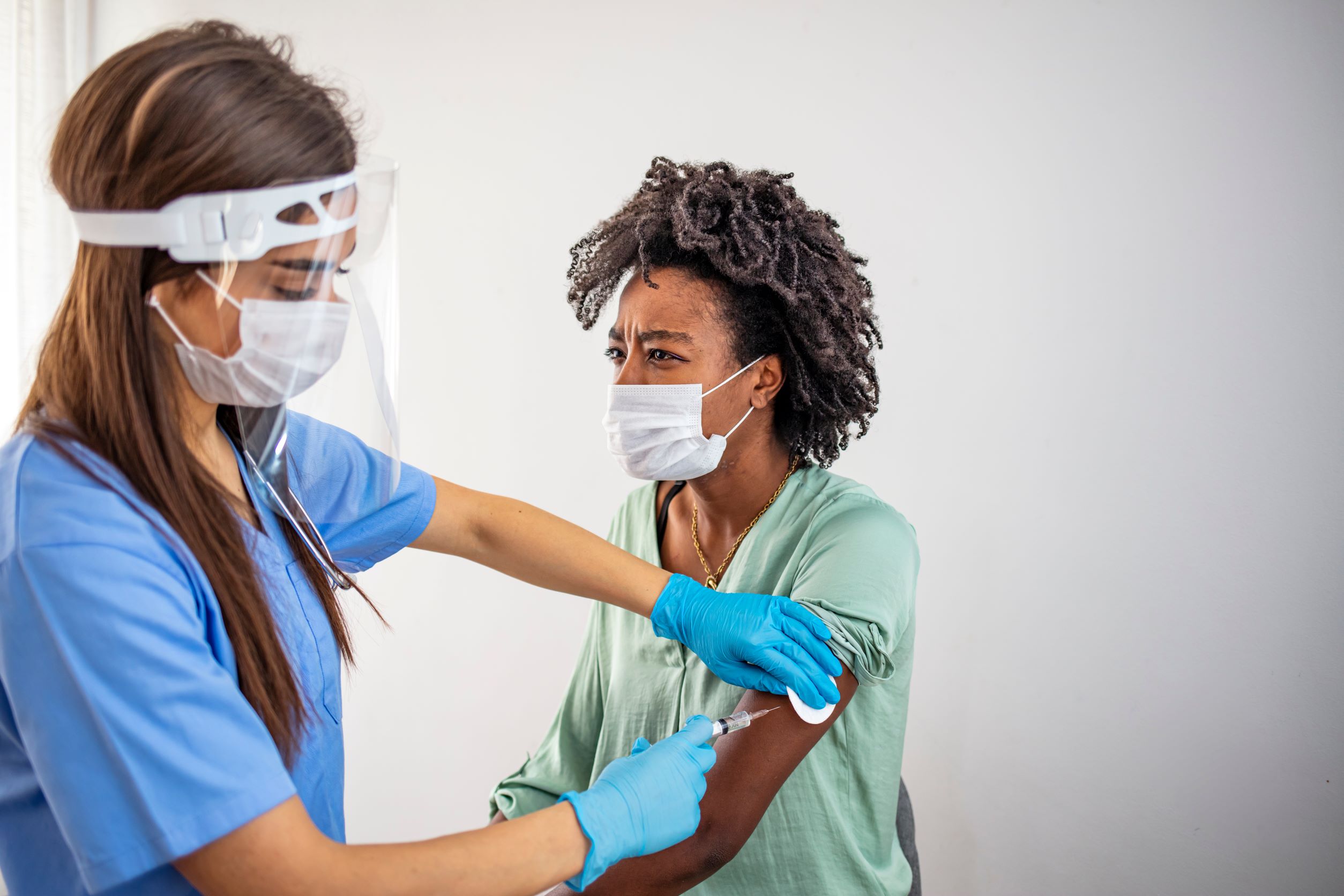 A woman receiving a vaccine while wearing a face mask.