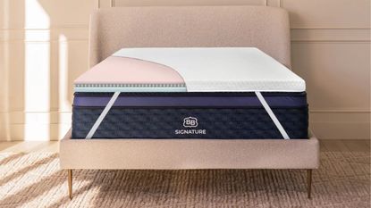 Brooklyn Bedding Microcoil Mattress Topper on a pink double bed with a pale peach panelled wall behind, and jute carpetting