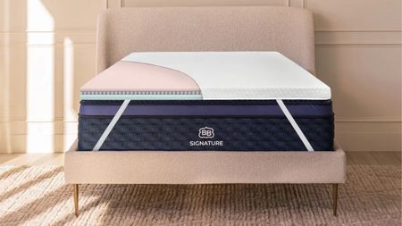 Brooklyn Bedding Microcoil Mattress Topper on a pink double bed with a pale peach panelled wall behind, and jute carpetting