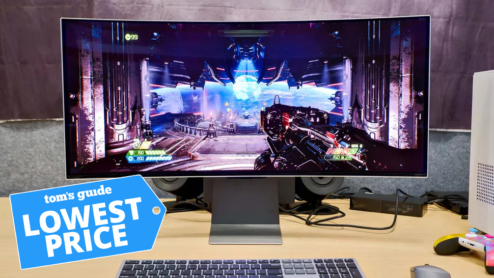 A photo of the Samsung Odyssey OLED G8 curved monitor, on a desk, with a game being played. There is a an image of a price tag in the bottom left highlighting that this monitor is on sale at its lowest ever price.