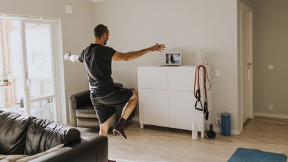 Man balancing on one foot in bedroom