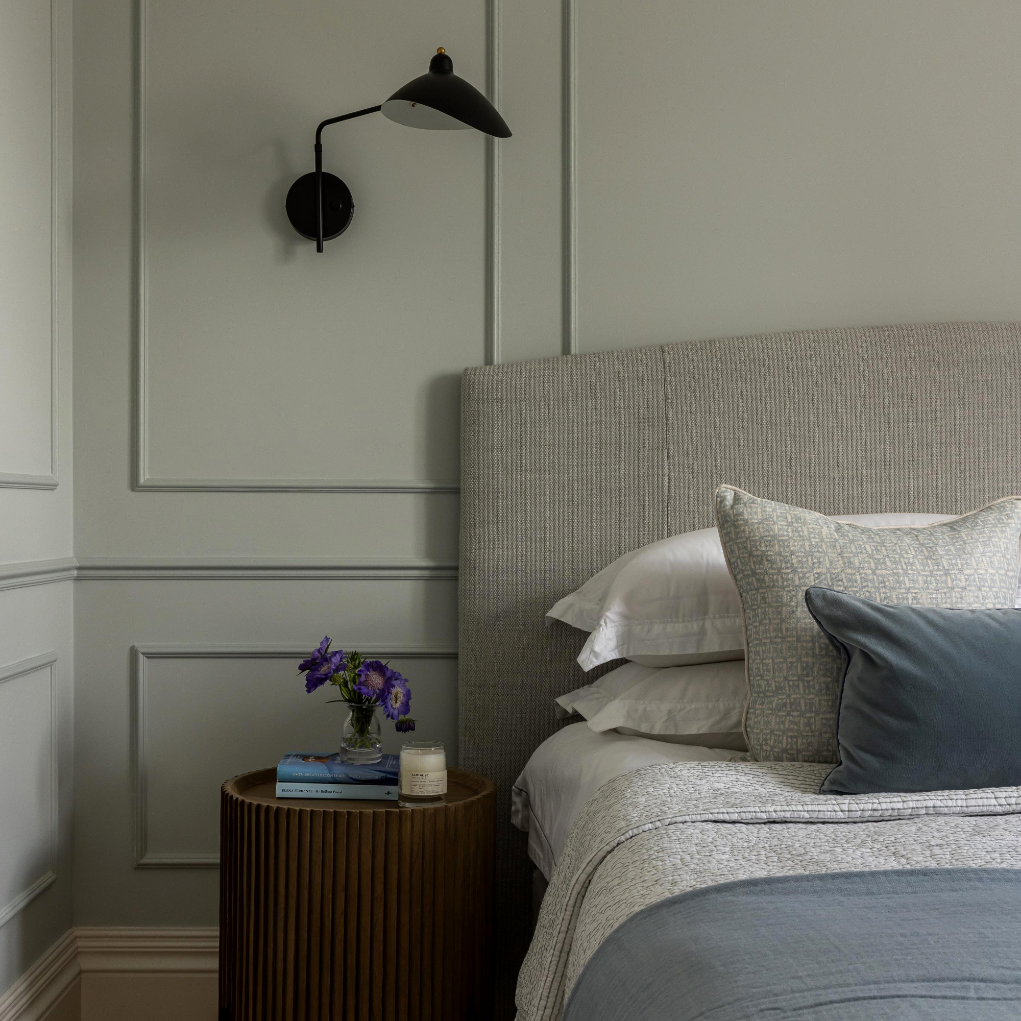 A bedroom designed by Lara Clarke Studios featuring a panelled wall