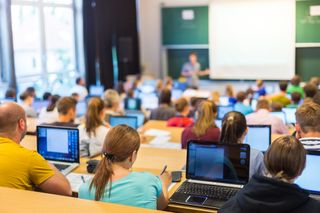 A lecture hall filled with students using laptops