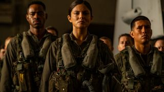 Jay Ellis, Monica Barbaro, and Danny Ramirez stand lined up in a hangar