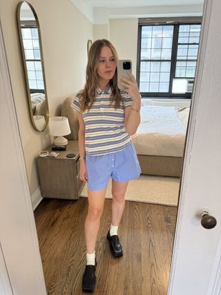 Nikki Chwatt wears blue striped shorts, a striped polo shirt, ivory ankle socks, and square-toe black loafers.