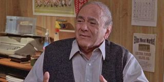 Michael Constantine looks concerned, sitting at his desk, in My Big Fat Greek Wedding.