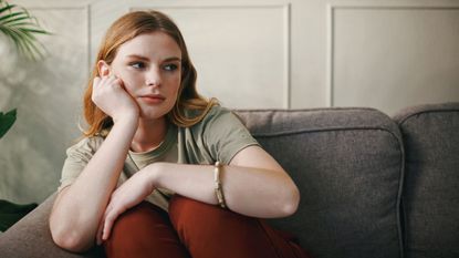 Shot of a young woman looking bored on brown sofa