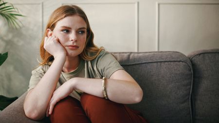 Shot of a young woman looking bored on brown sofa