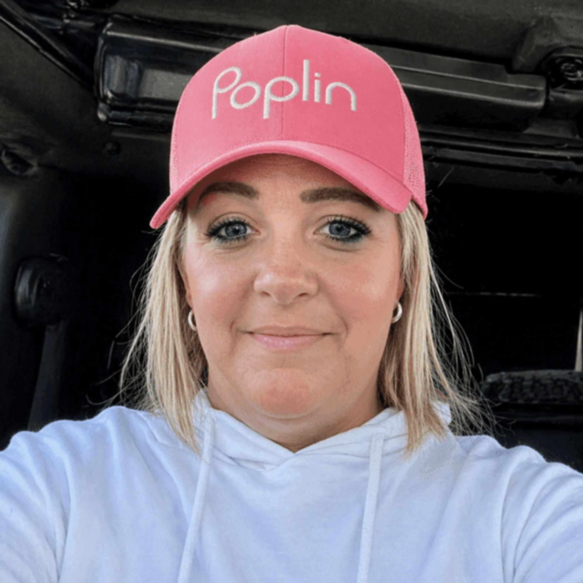 A headshot of Stacee Parker wearing a white hoodie and pink cap