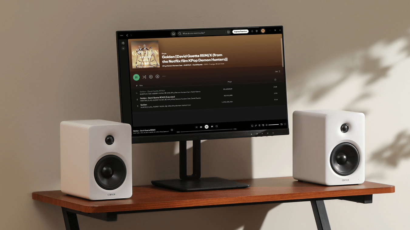 A press image of the Edifier M90 white bookshelf speakers either side of a desktop