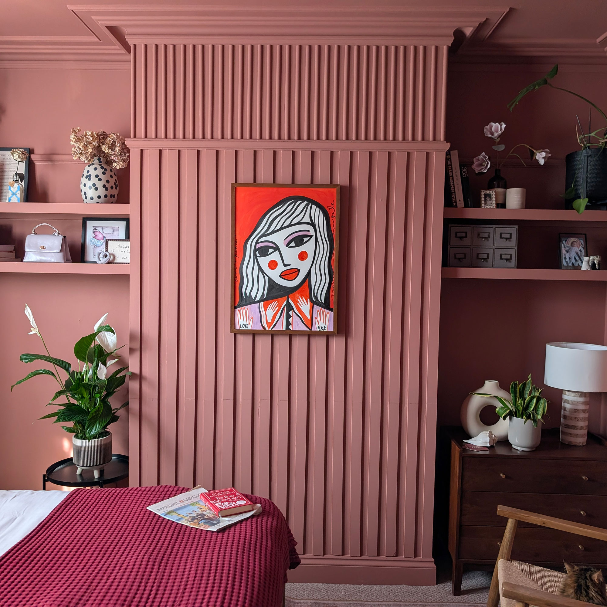 Bedroom with pink wall panelling with artwork on wall