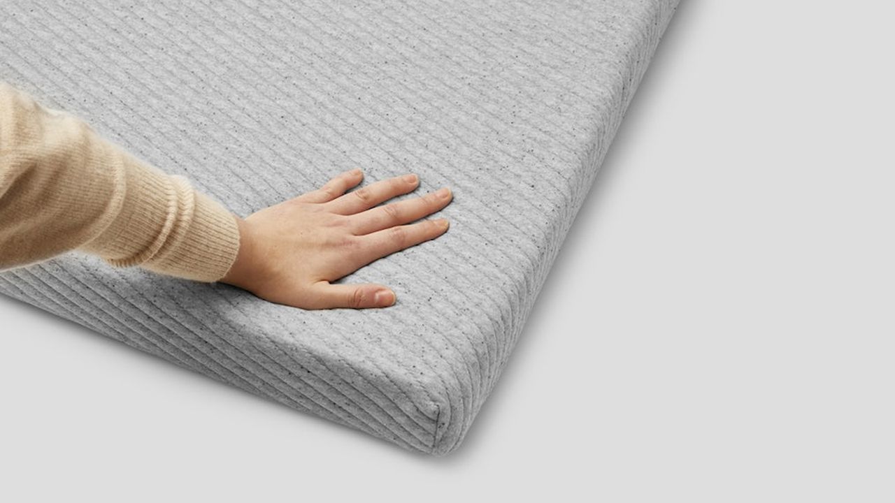 Person with their hand on the Casper Comfy Mattress Topper.