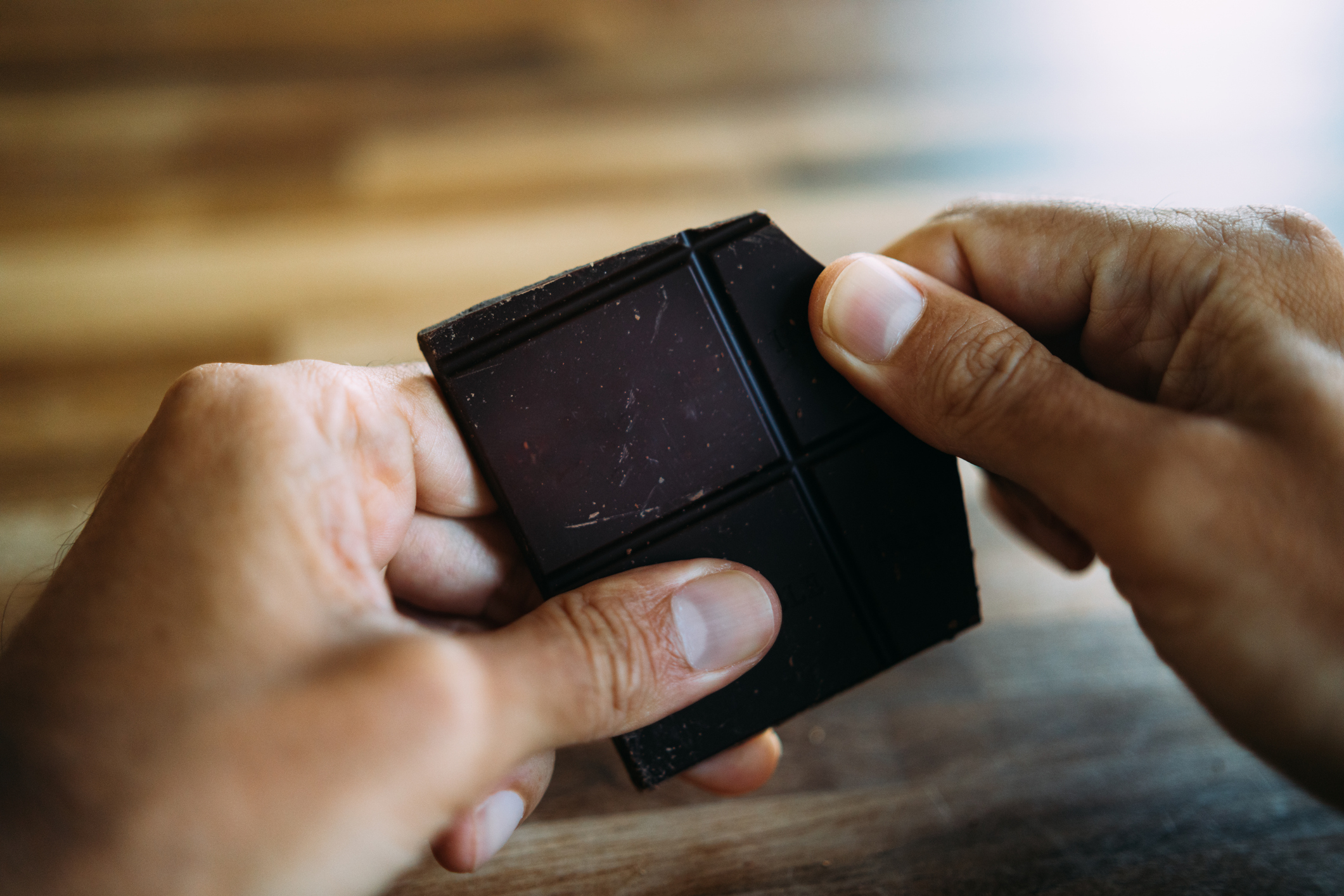 Hands breaking off a piece of dark chocolate