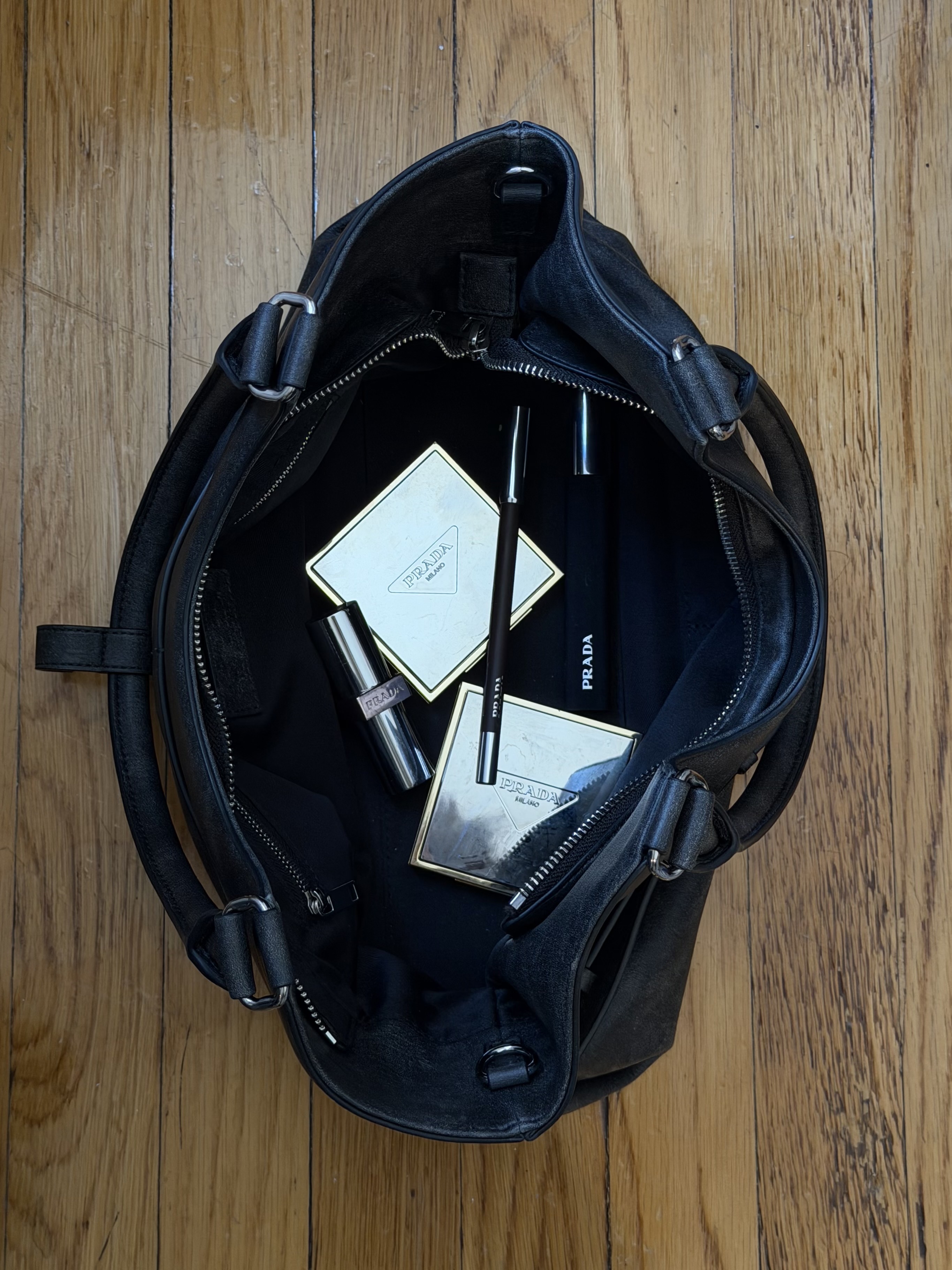 An image of the inside of WWW associate beauty editor Alyssa Brascia's purse with Prada beauty products inside.