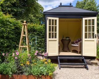 A small English cottage garden with Summerhouse Shepherds Hut in gravel garden - working from home office