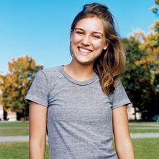 julia dewahl smiling in the park in a gray t shirt and workout pants