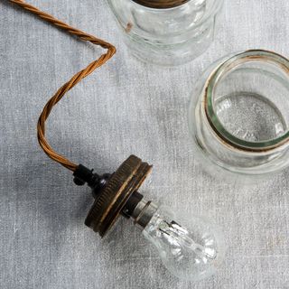 bulb with yellow wire and glass jar on grey surface