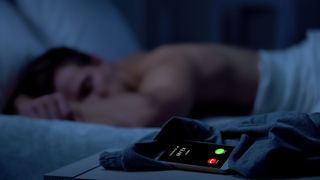 A man asleep next to a phone lit up with a call from 'My Ex'