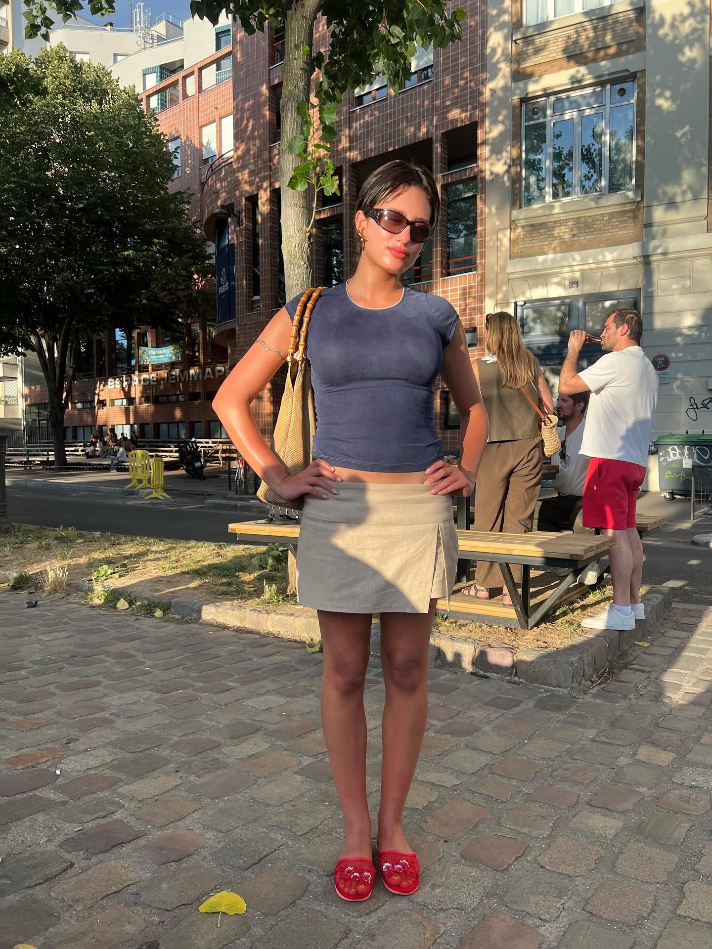 @g_yasein wearing a crewneck top, mini skirt, red slippers, and a bamboo handle bag