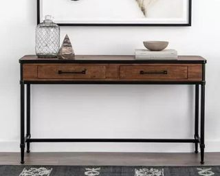 a Pottery Barn console table with drawers, with minimal accessories and artwork behind it on a white wall