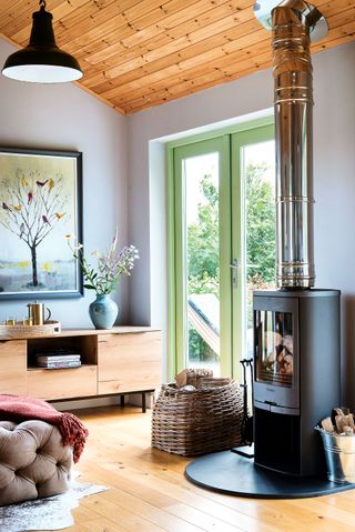 woodburner and picture windows with wooden sideboard and wooden floor