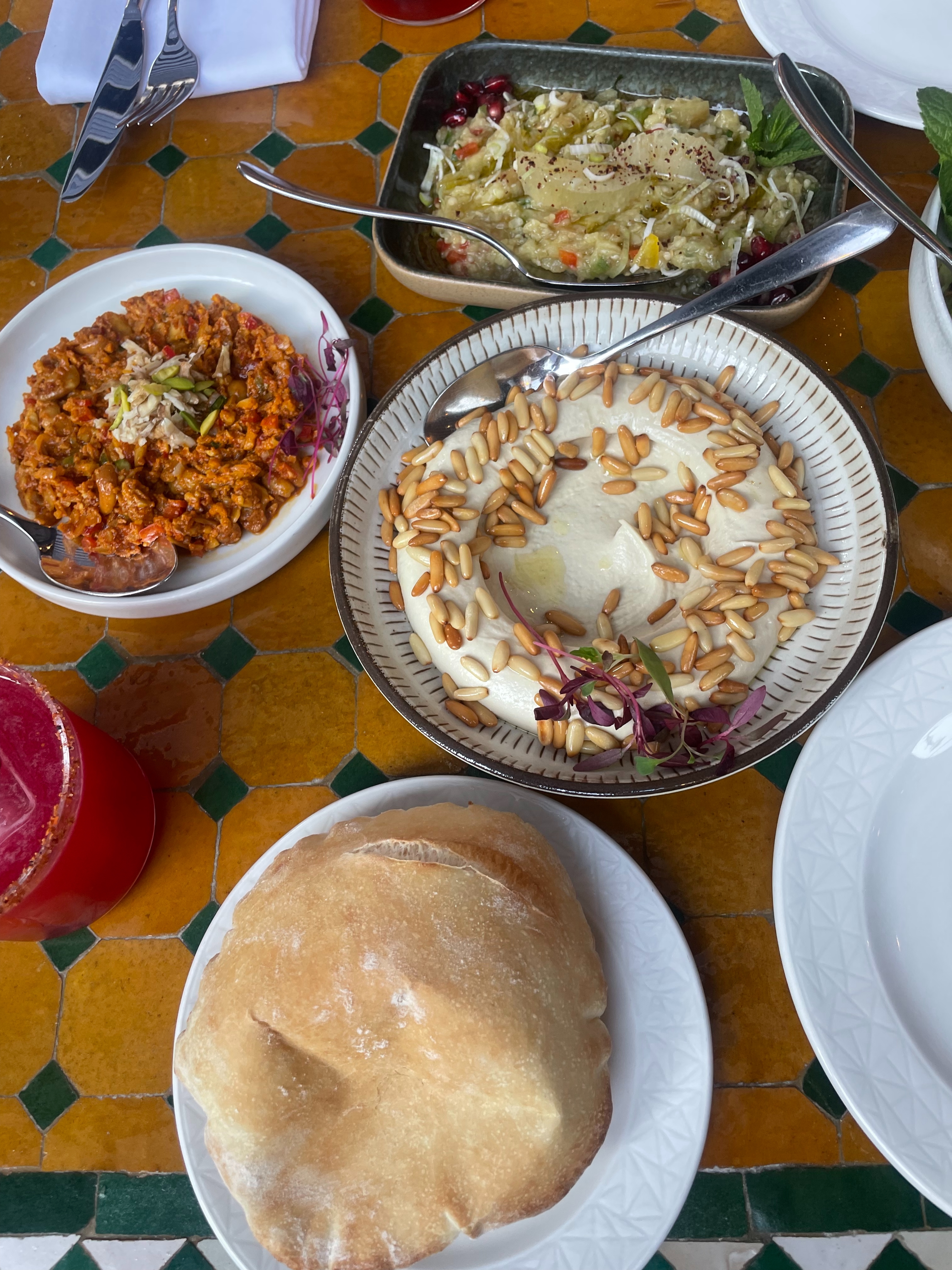 an image of the starting cold mezze at Ishbilia, with pita, hummus, and other small plates