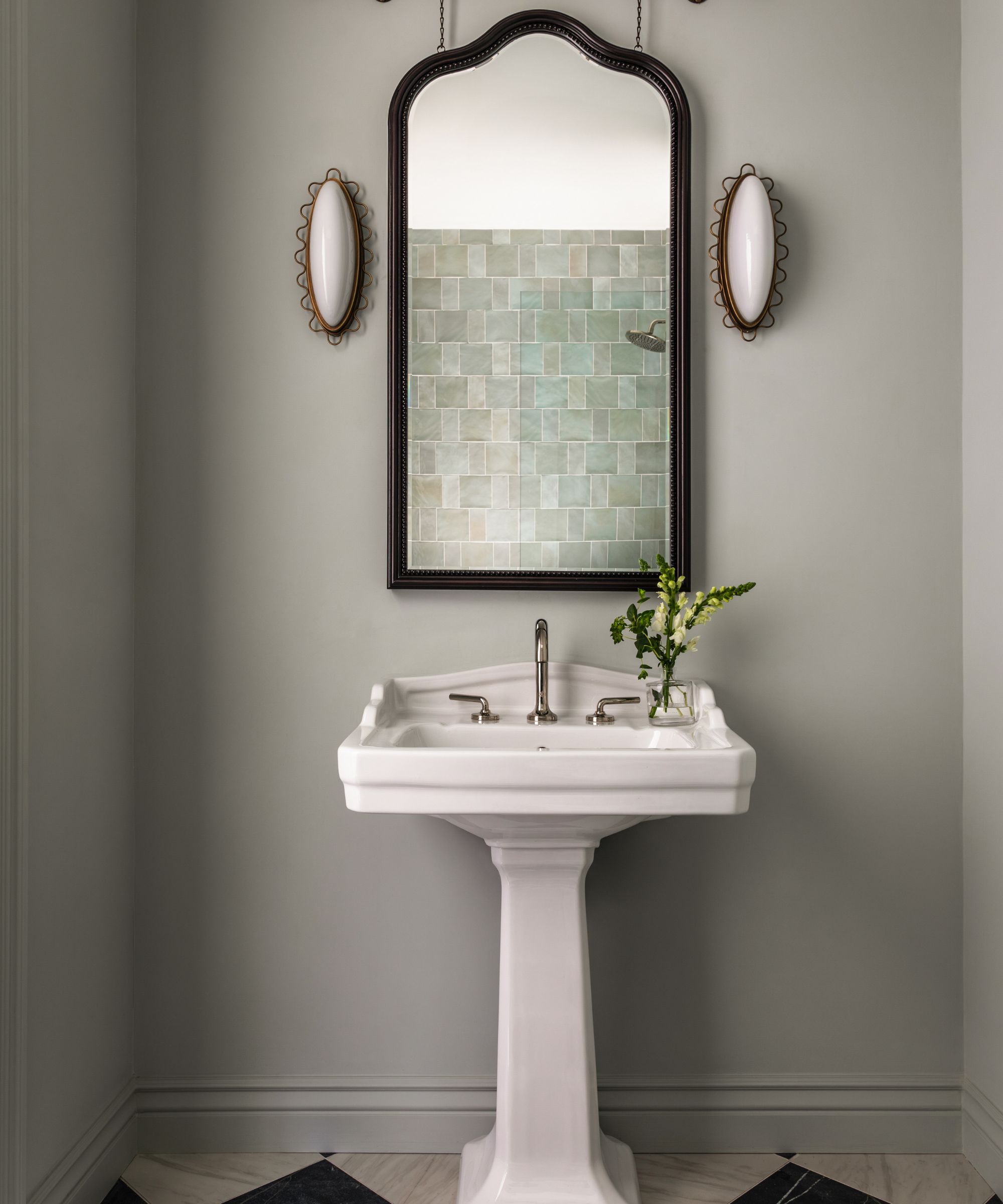 A small bathroom with Benjamin Moore Smokey Green on the walls, a dark wood mirror, and a white pedestal sink