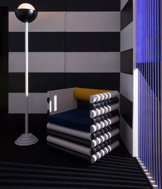 Black, white and yellow wooden lounge chair in front of black and white striped wall